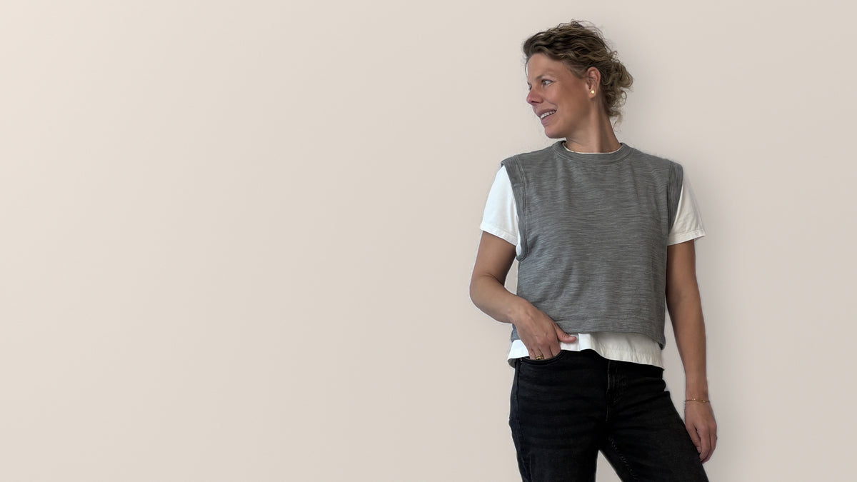 Woman wearing the EVEN sweater vest from Y Patterns over a white t-shirt with black jeans, sewing pattern for women